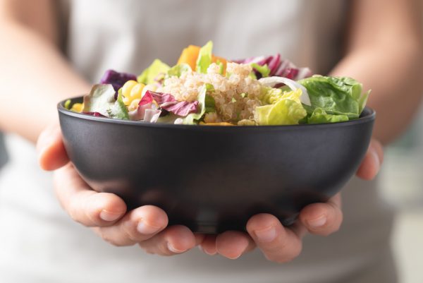 Fresh organic vegetables with full of life quinoa seed in bowl holding by hand, Healthy nutritious Vegan food