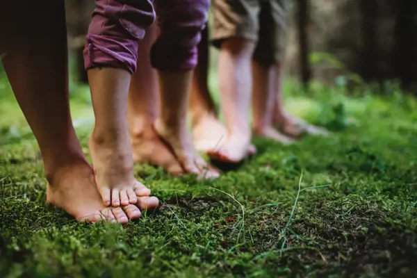 Close-up of a child's bare feet resting on an adult's feet on green grass, symbolizing grounded support and harmonized family relationships