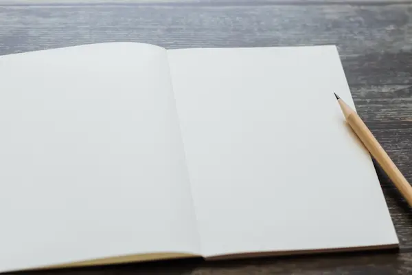 A blank white journal and natural pencil at ThaoQi, symbolizing the start of transformation coaching and the path to a brand new you